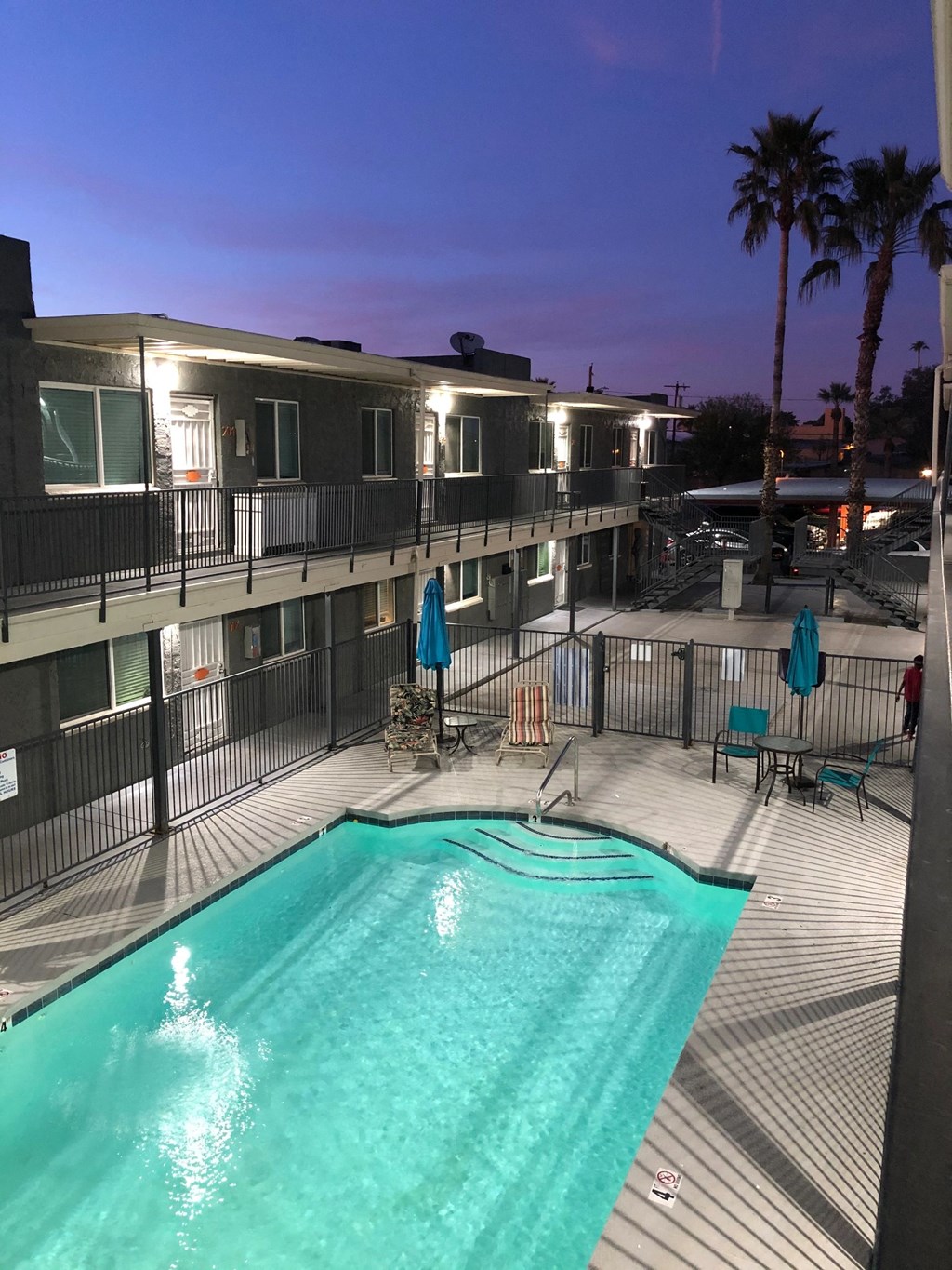 a swimming pool at night in a hotel with palm trees