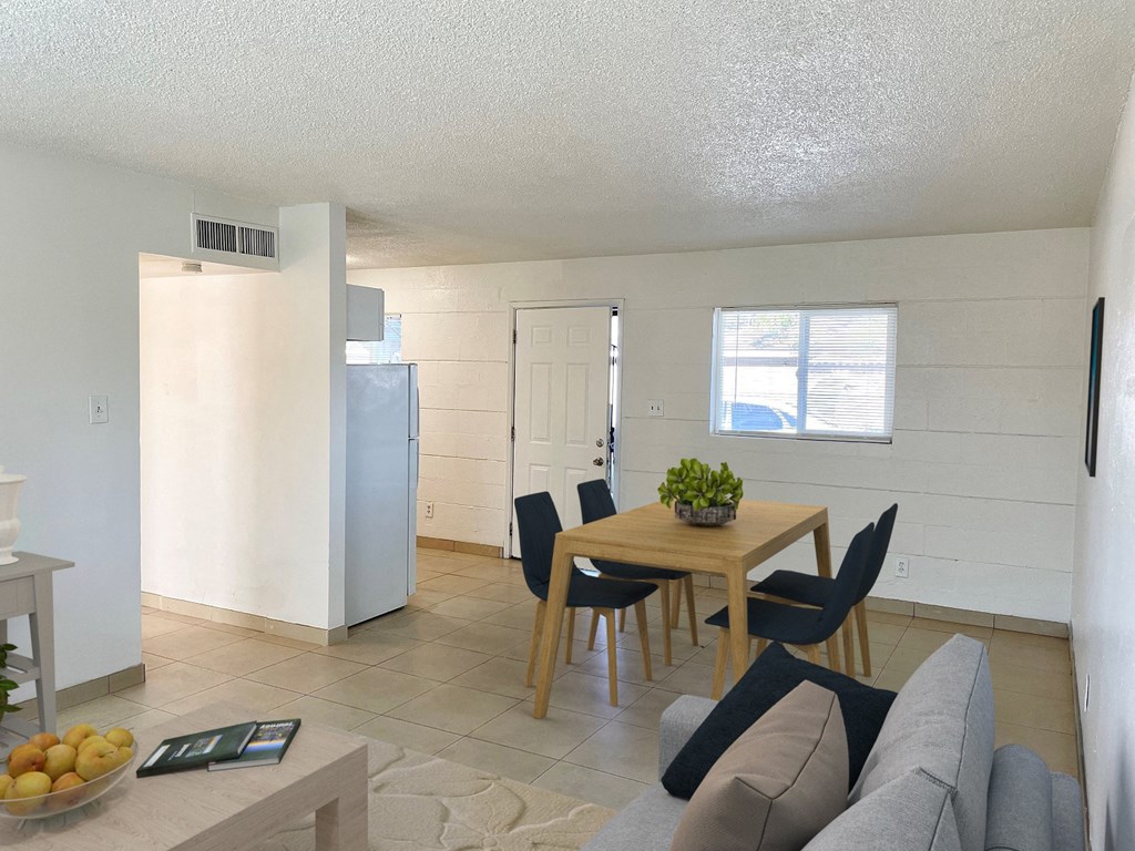 a living room and dining room with a table and a refrigerator