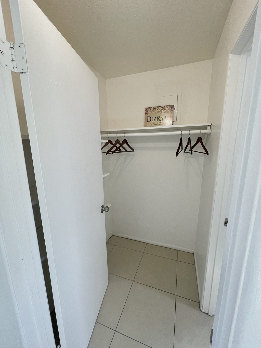 an empty closet in a room with white walls and a white tiled floor