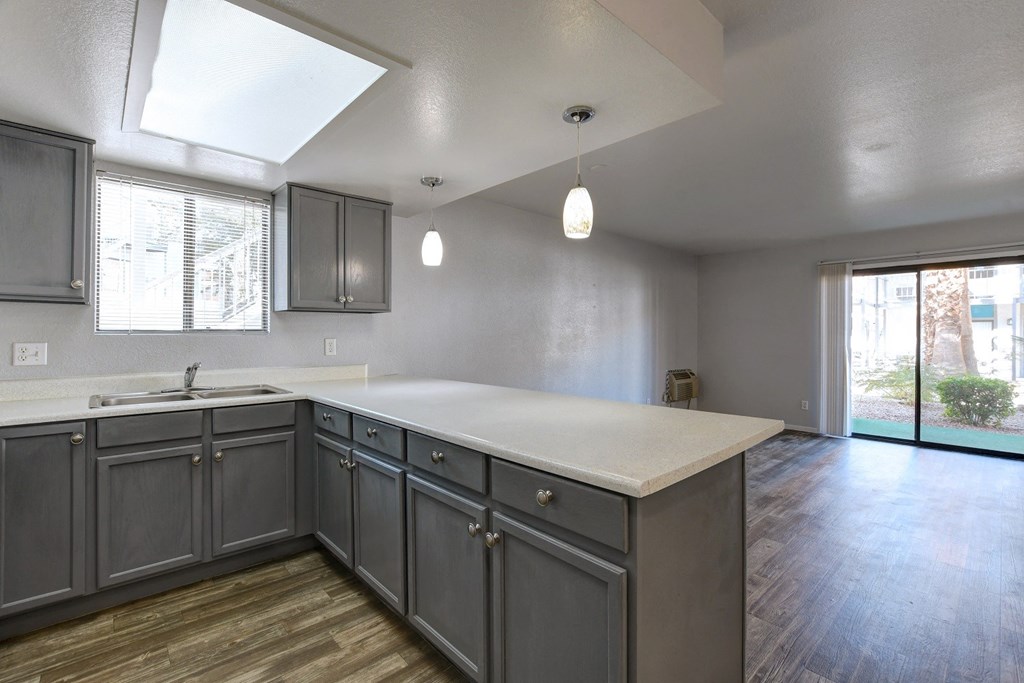 an empty kitchen with gray cabinets and a white counter top