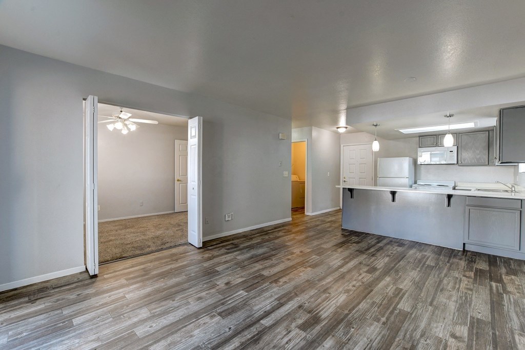 the living room and kitchen of an apartment with wood flooring