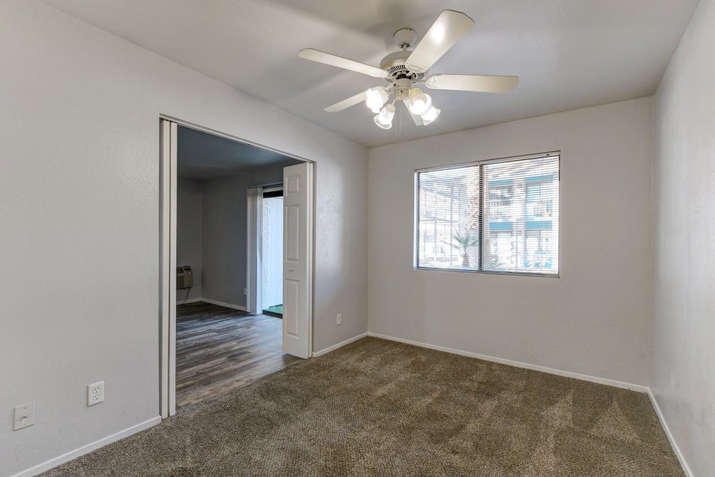 an empty living room with a ceiling fan and a window