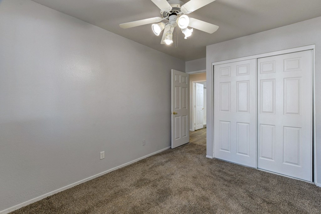 an empty room with carpet and a ceiling fan
