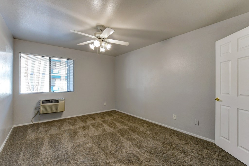 an empty living room with a ceiling fan and a window
