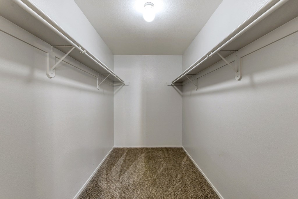an empty room with white walls and a carpeted floor and two white hangers