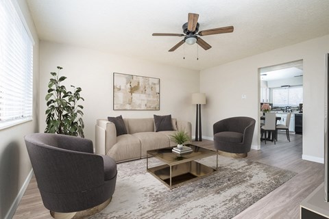 a living room with a couch and chairs and a ceiling fan