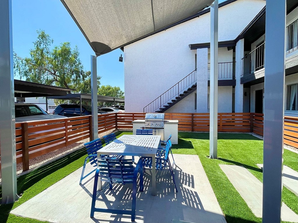 a patio with a table and chairs and a grill