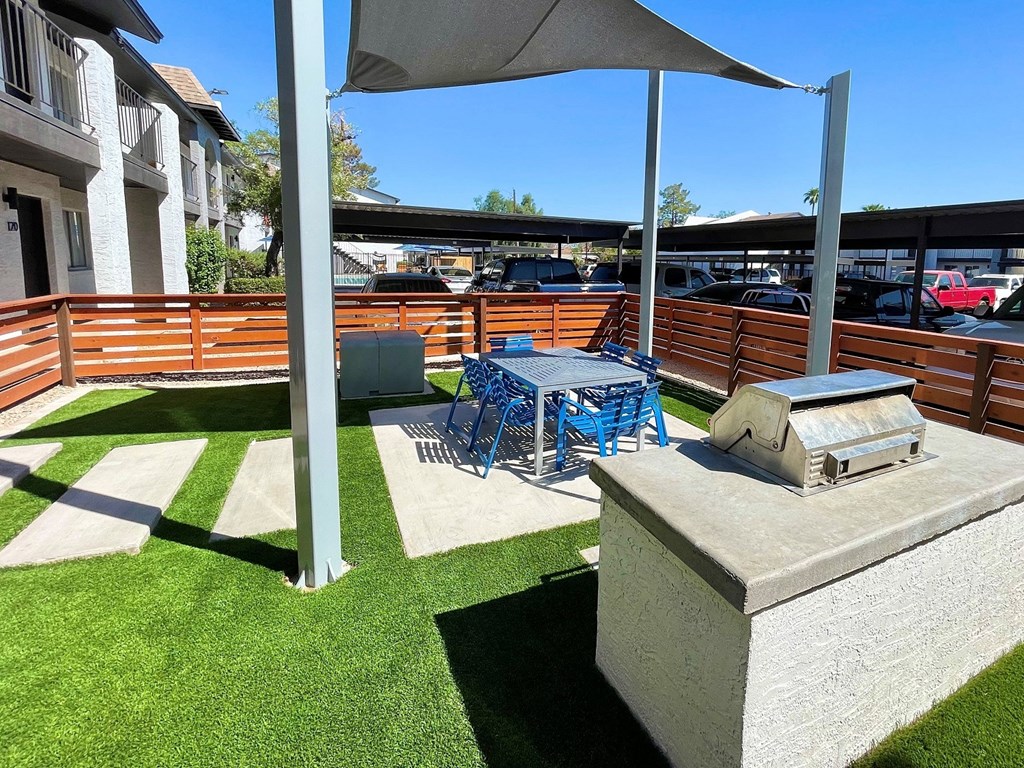a patio with a grill and a table and chairs