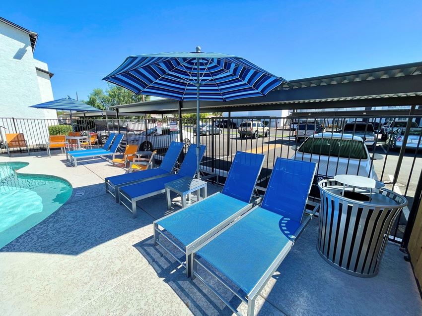 a pool with blue lounge chairs and umbrellas