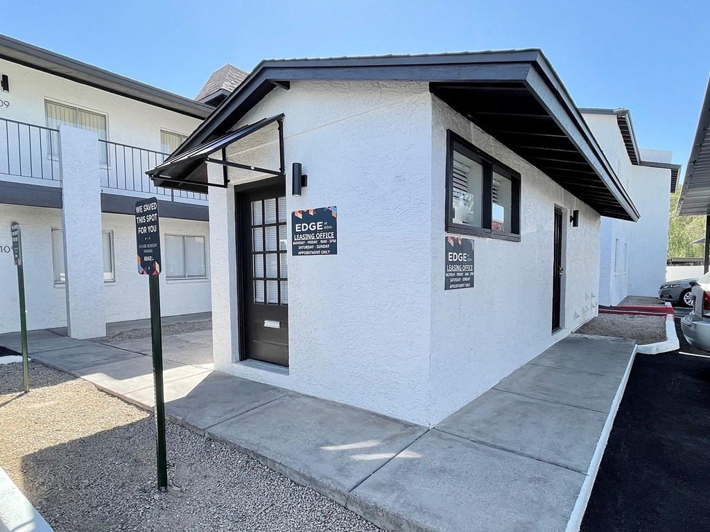 a white building with a black awning and a parking lot in front of it