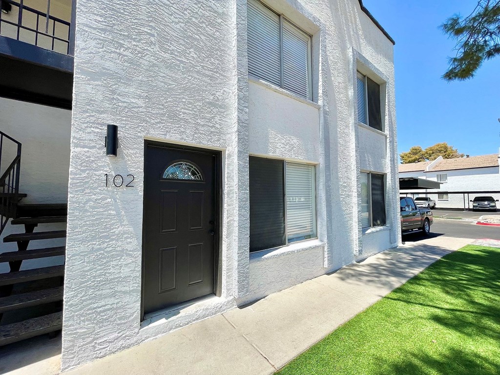 a white building with a black door and a green lawn