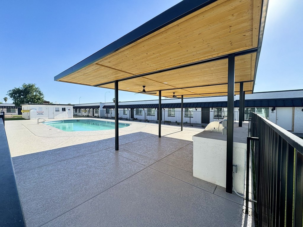 a patio with a pool and a building in the background