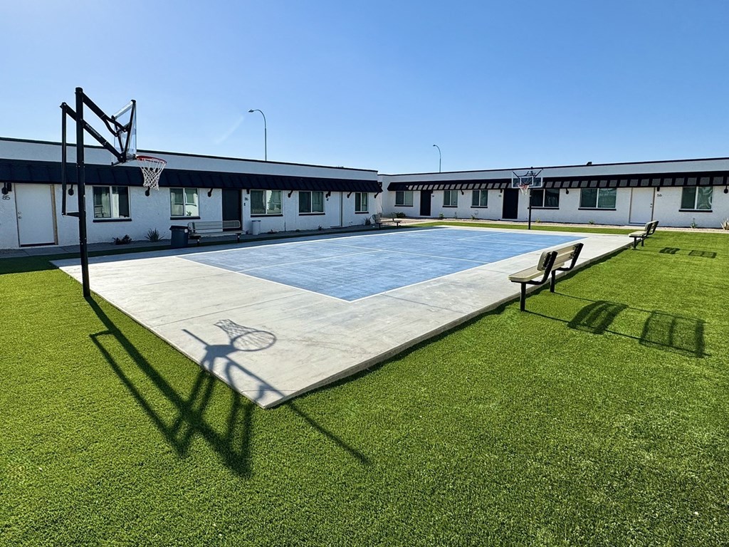 a basketball court in front of a school with a bench