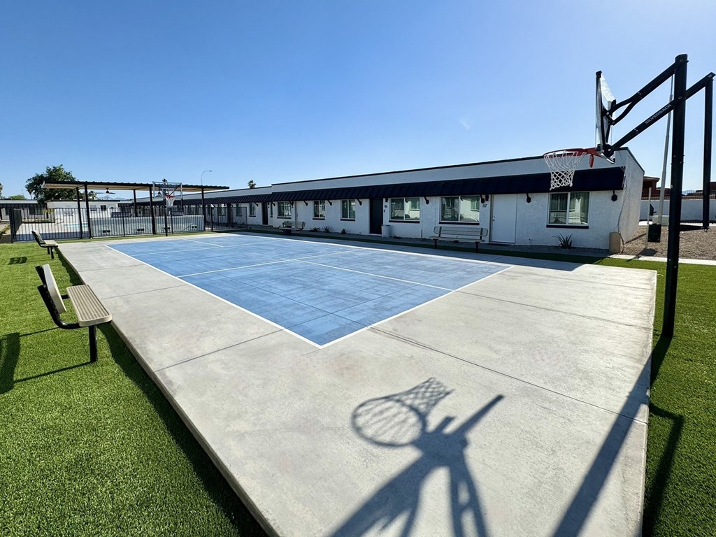 a basketball court in front of a building with a shadow of a tennis racket