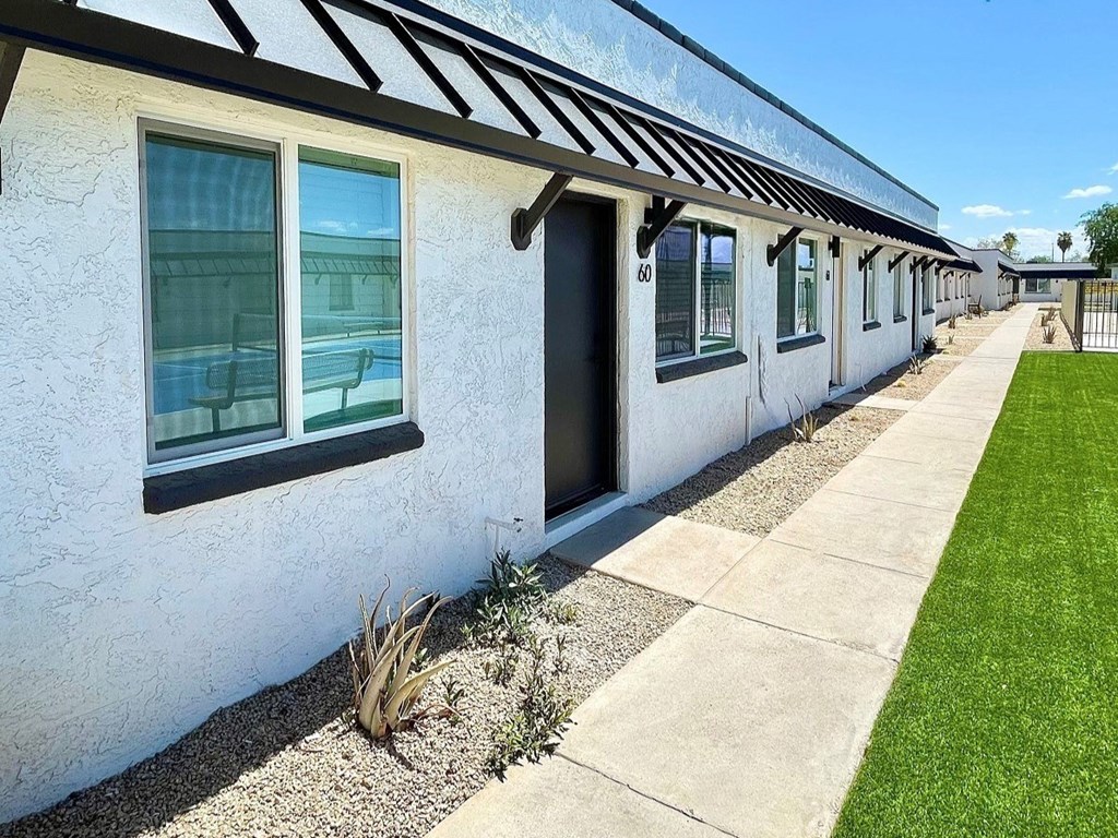a view of the outside of a building with a sidewalk and grass