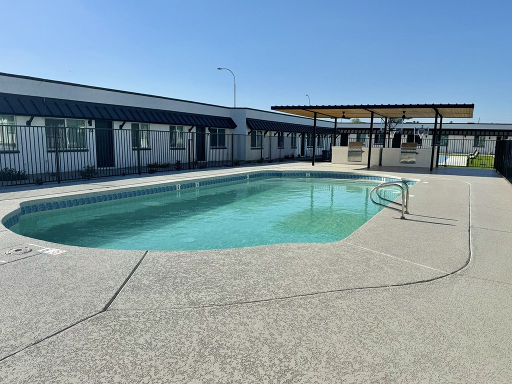 a swimming pool at a motel with a building in the background