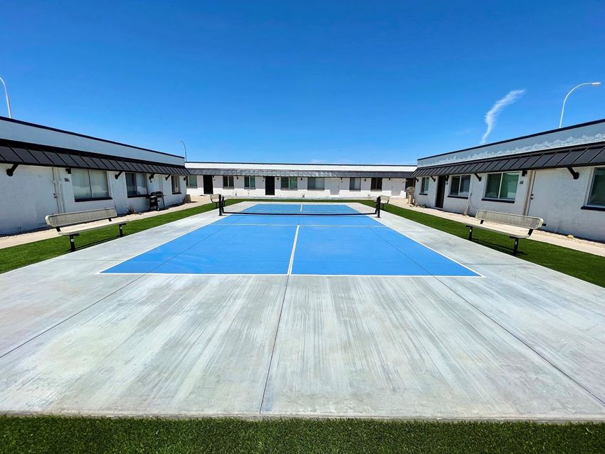 a blue tennis court in front of a white building with a blue sky in the background - Photo Gallery
