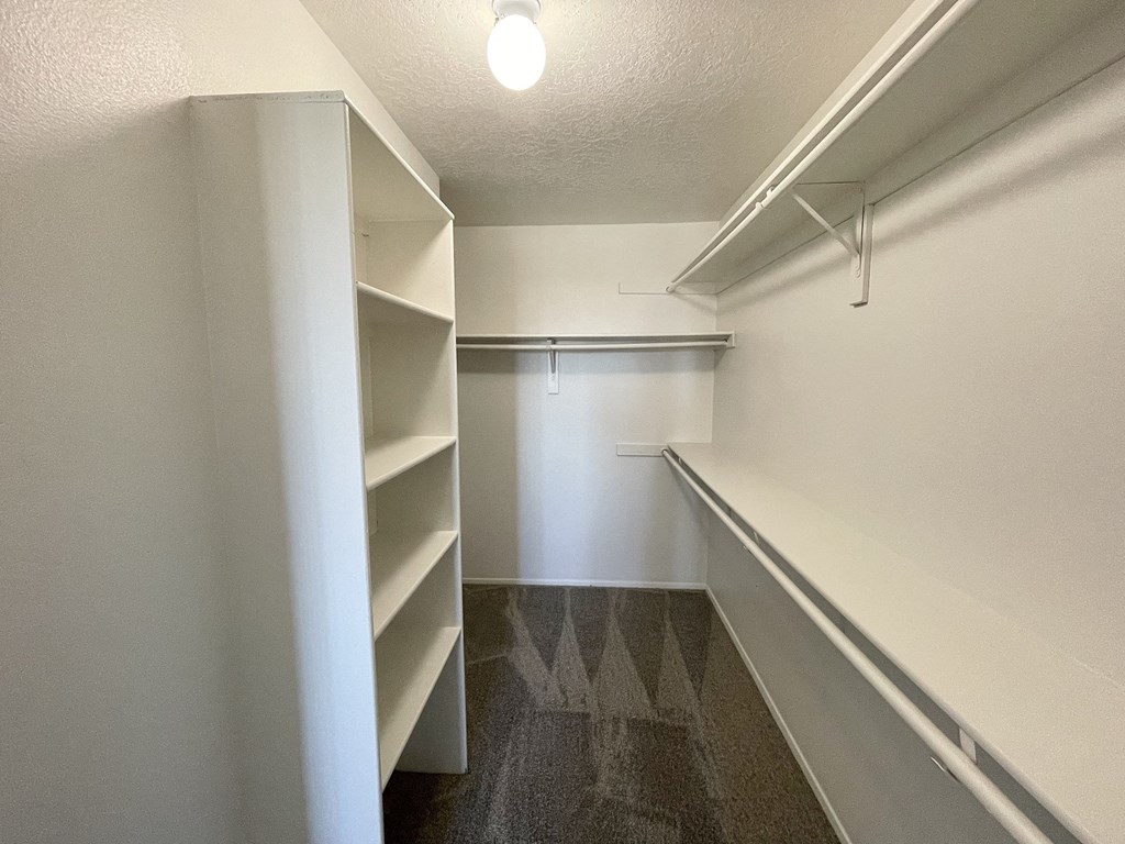 a walk in closet with shelves and a white wall