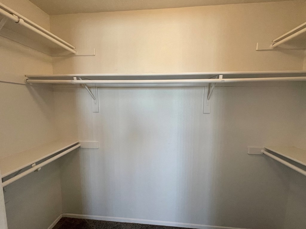 a walk in closet in an empty room with white walls