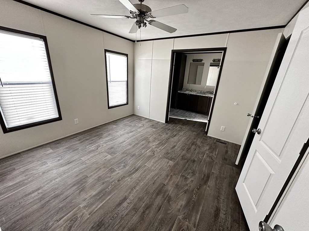 an empty living room with wooden floors and a ceiling fan