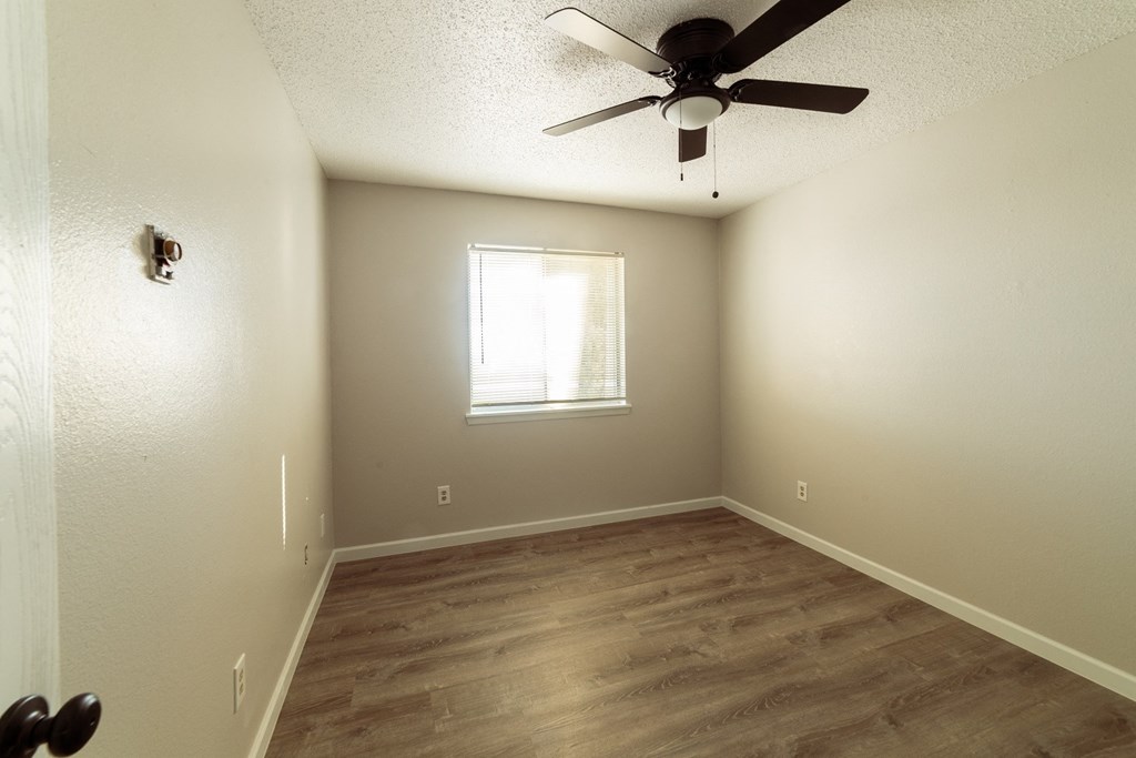 an empty room with a ceiling fan and a window