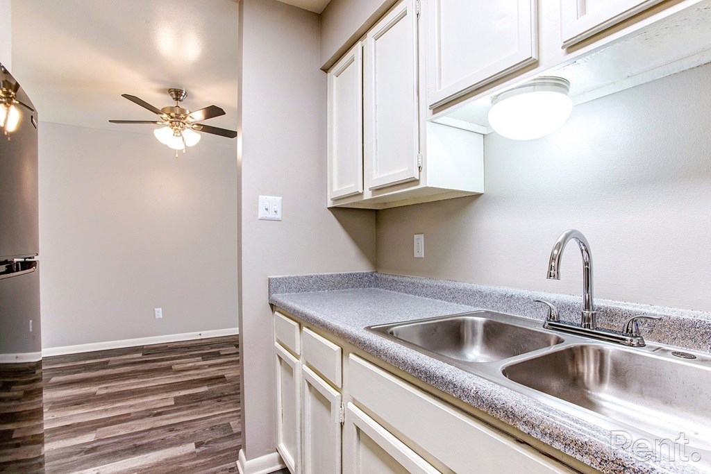 a kitchen with white cabinets and a sink and a ceiling fan