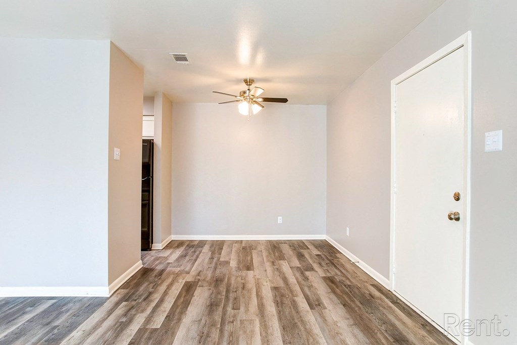 an empty living room with white walls and a ceiling fan