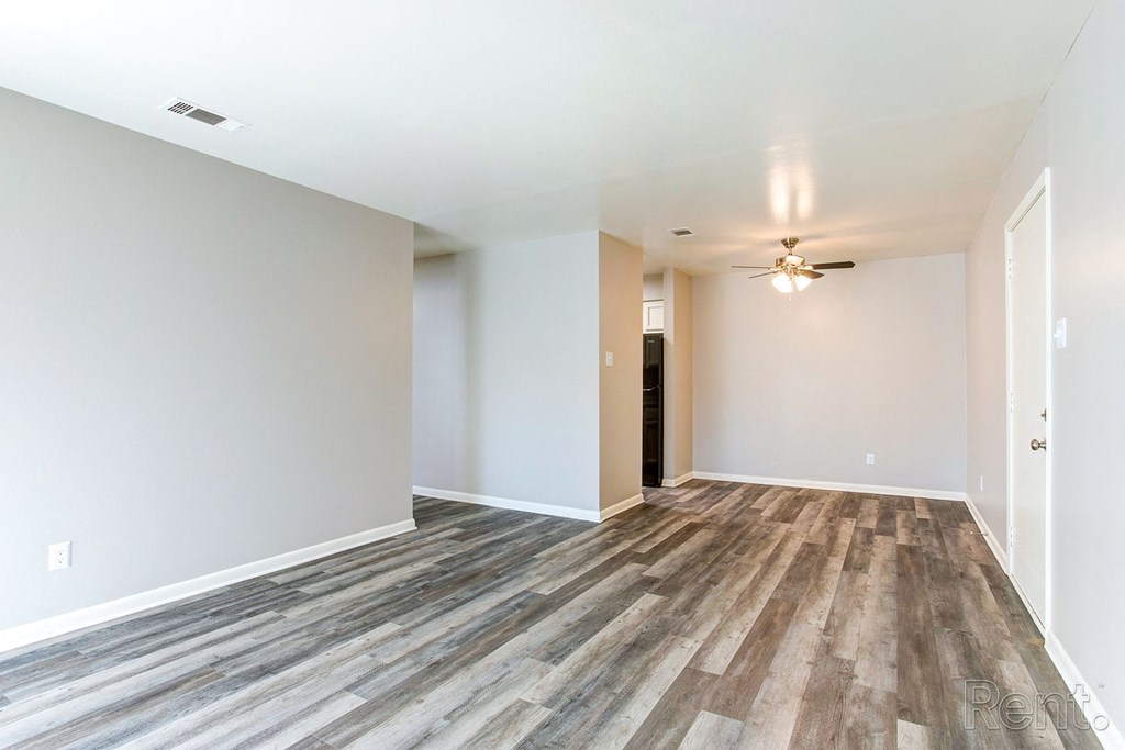 an empty living room with wood flooring and a ceiling fan