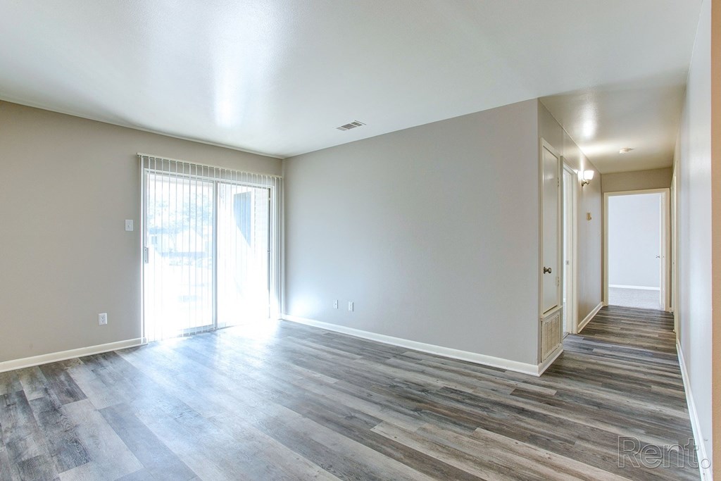 an empty living room with wood floors and white walls