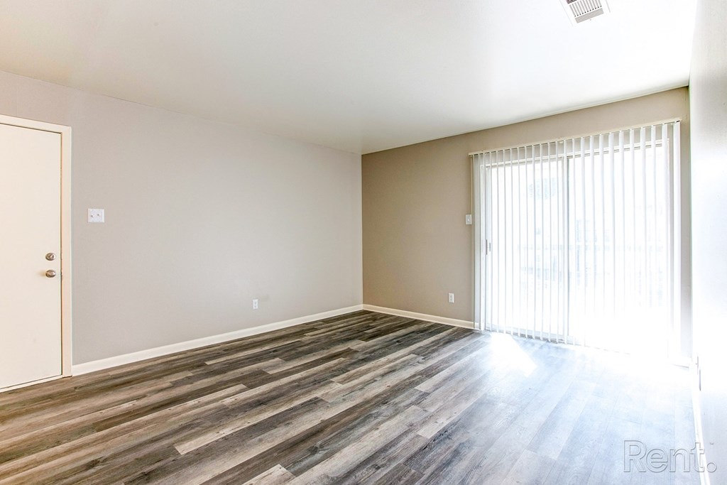 an empty living room with wood floors and a large window