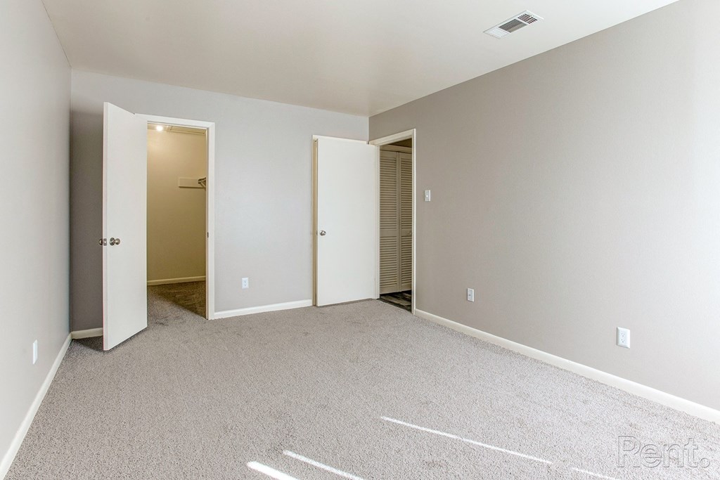 a bedroom with a carpeted floor and two closets