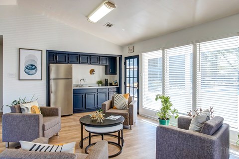 a living room with couches and chairs and a kitchen with blue cabinets