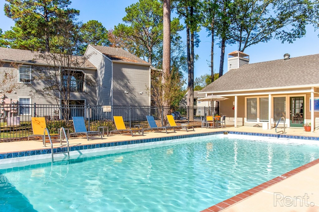 a swimming pool with yellow chairs and a house in the background