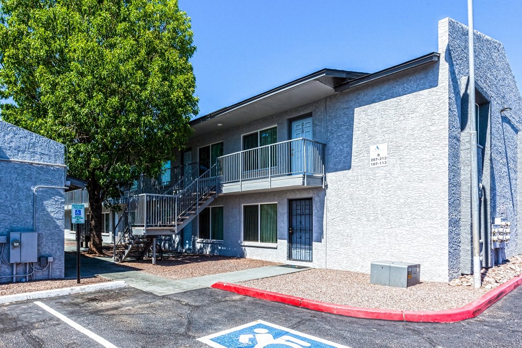 a white building with a red curb and a tree
