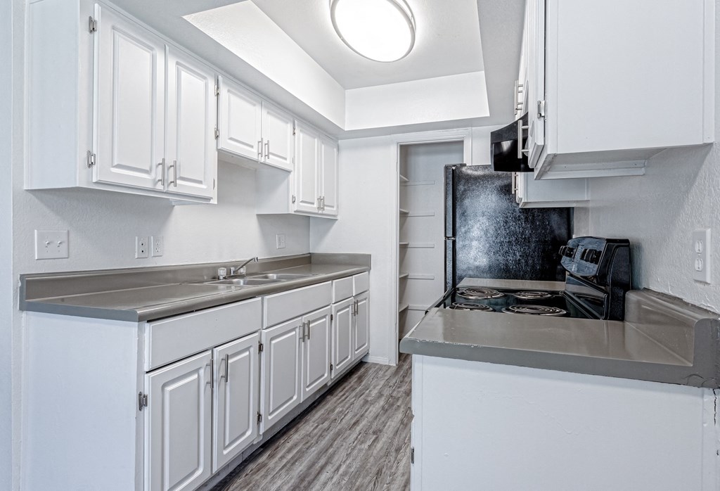 an empty kitchen with white cabinets and stainless steel counter tops