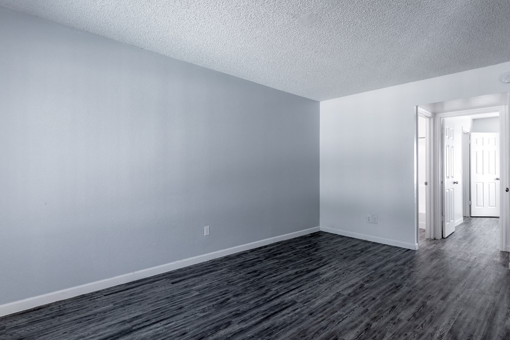 an empty living room with wood flooring and white walls