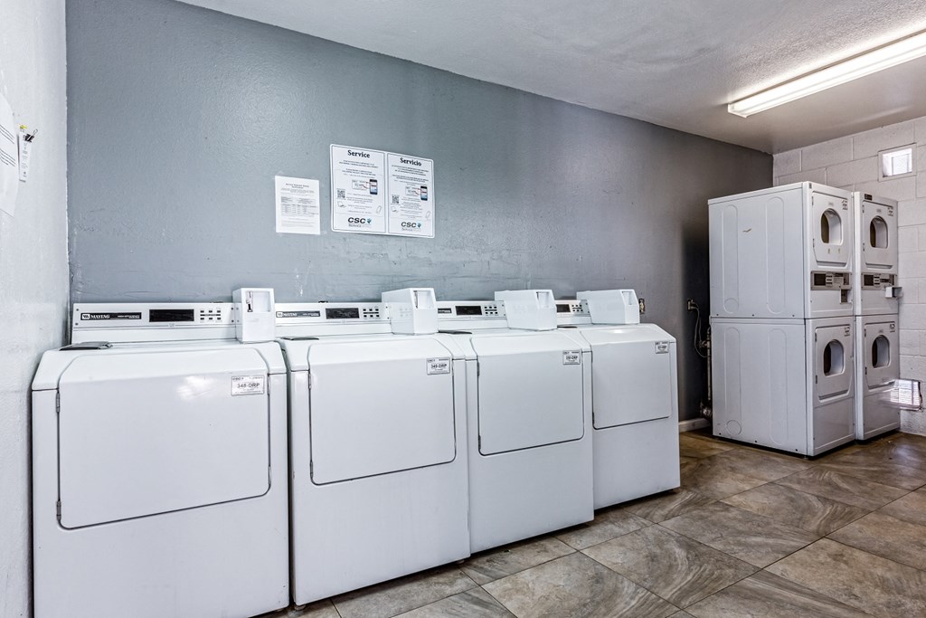 a row of white washers and dryers in a laundry room