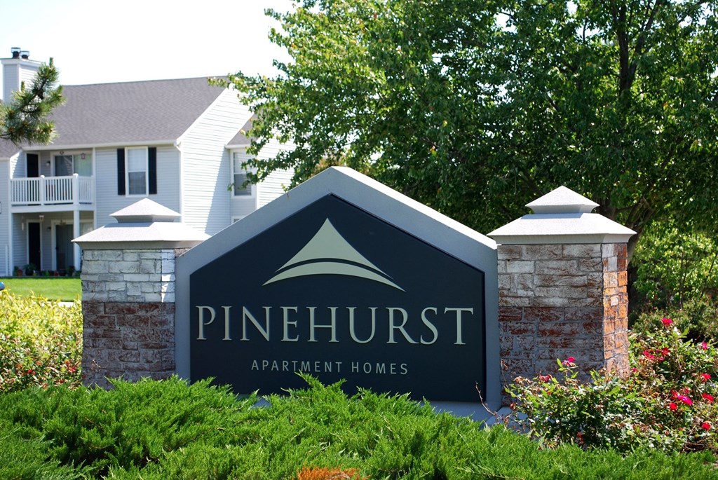 a sign that says pinehurst apartment homes in front of a house