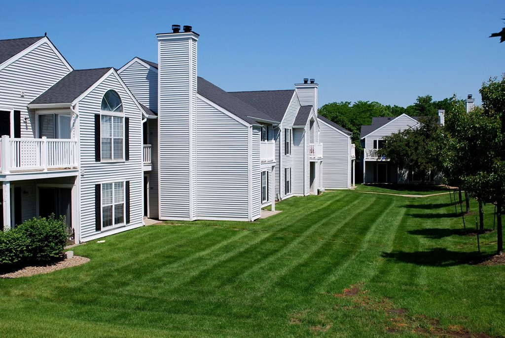 a row of houses with white siding and manicured lawns