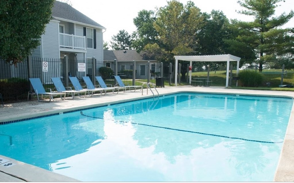 a swimming pool with chaise lounge chairs and a gazebo in front of a