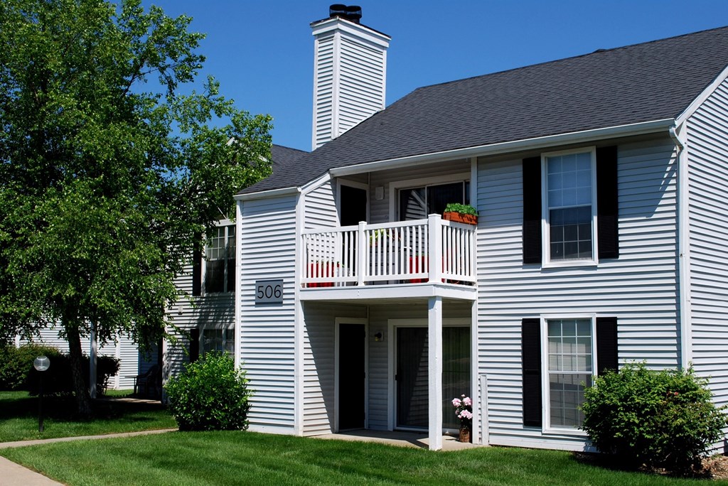 a white house with a gray roof and a white balcony