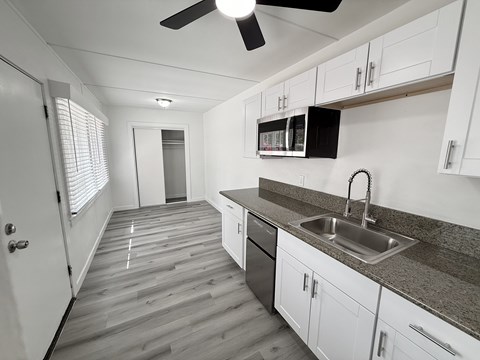 A kitchen with white cabinets and a black fridge.