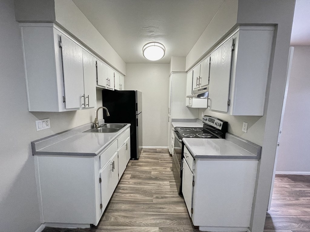 an empty kitchen with white cabinets and a black refrigerator