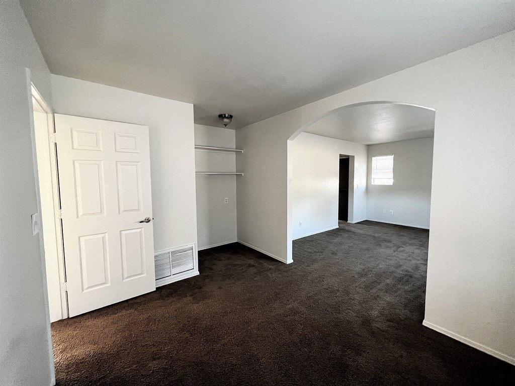 an empty living room with a white closet and a door