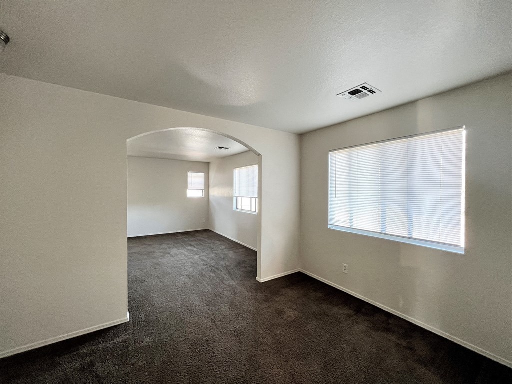 an empty living room with a large window and white walls