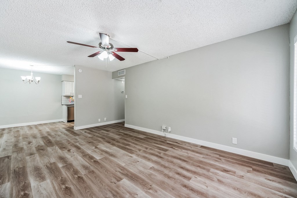 an empty living room with a ceiling fan
