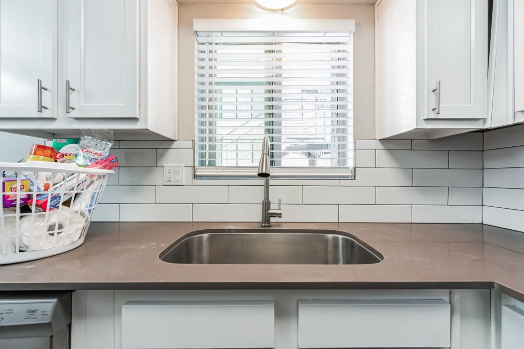 a small kitchen with white cabinets and a window