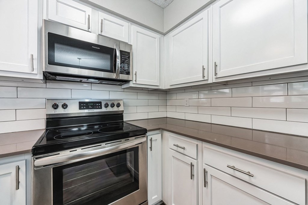 a kitchen with white cabinets and a stainless steel stove