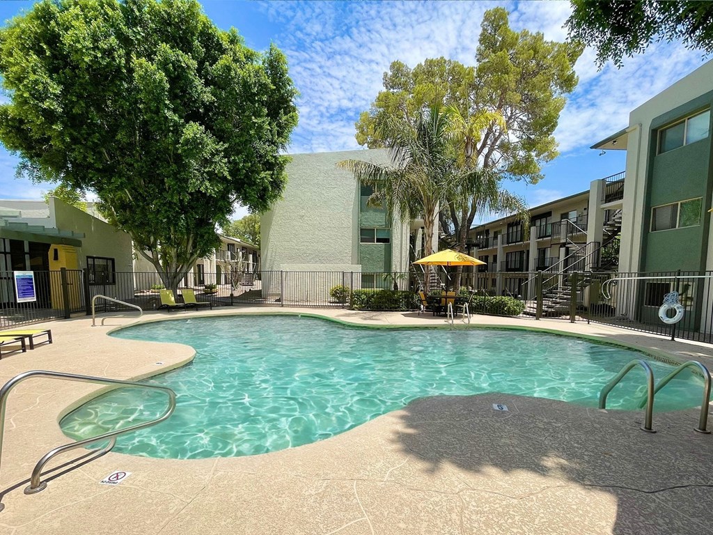 a swimming pool with a yellow umbrella in front of a building