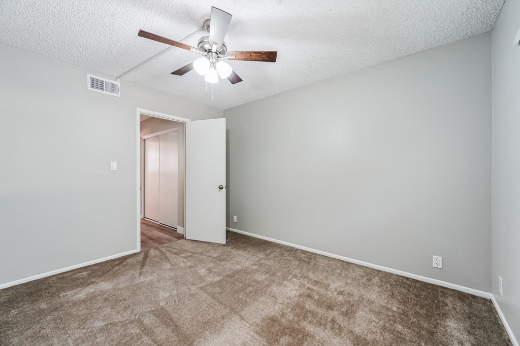 an empty bedroom with a ceiling fan